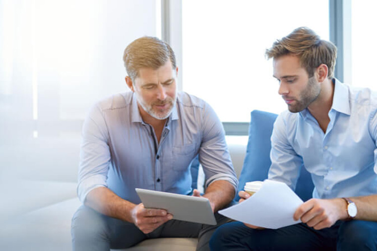 two men holding documents and talking about a plan